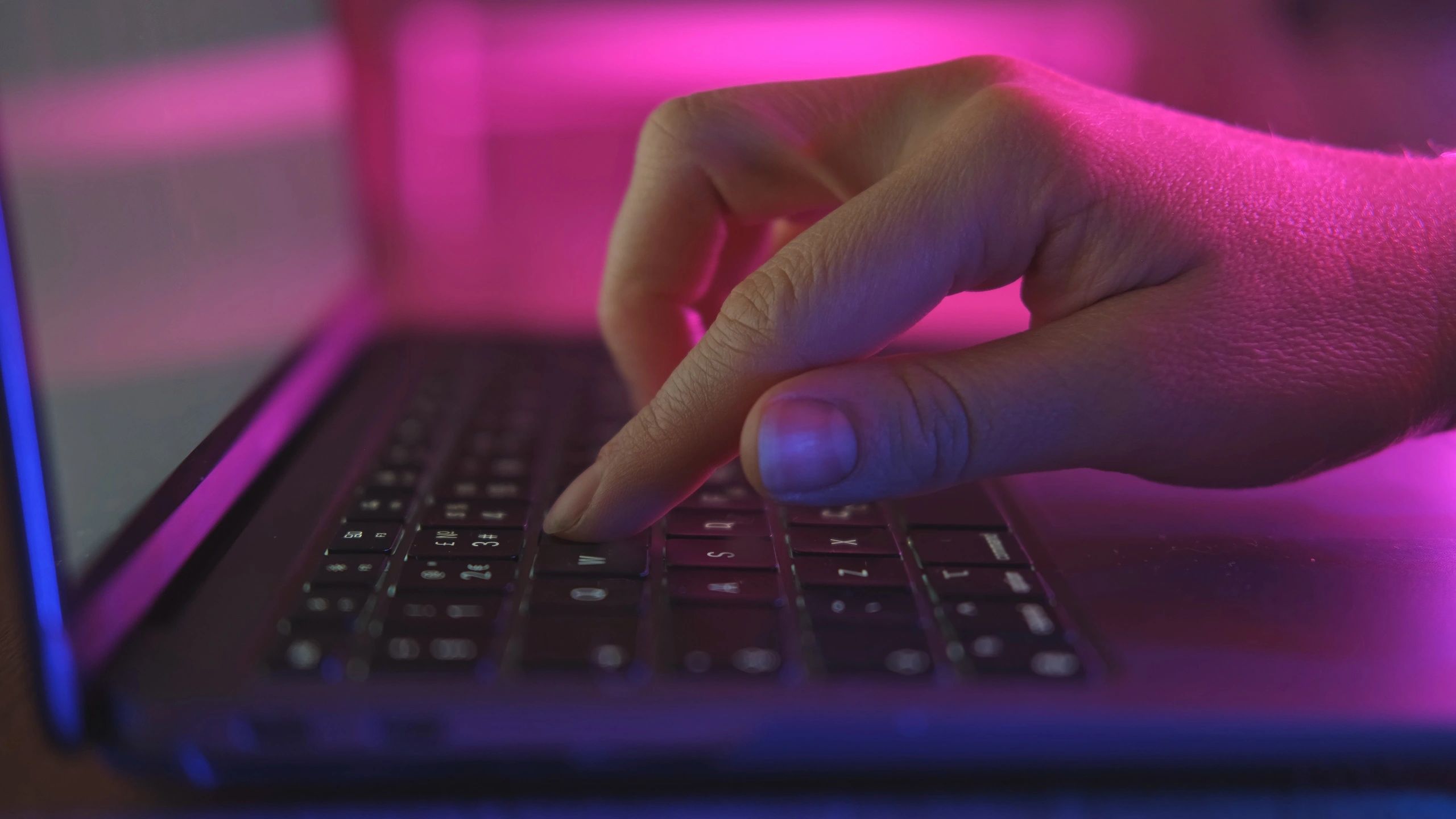 Developer typing on a laptop with code-focused lighting